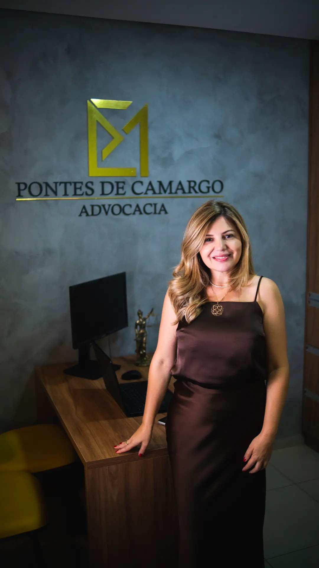 Magaly Camargo em frente ao logotipo da Pontes de Camargo Advocacia